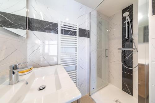 a white bathroom with a sink and a shower at Le Petit Appartement de Saint-Denis in Saint-Denis-dʼOléron