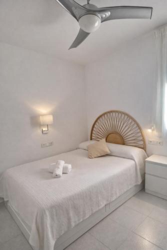 a white bedroom with a bed with a ceiling fan at Tramuntana apart in Calafell