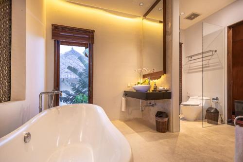 a bathroom with a tub and a sink and a toilet at Villa Sulastri - Tanah Lot in Tanah Lot
