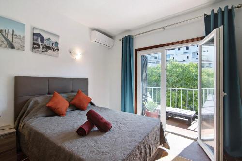 a bedroom with a bed with orange pillows and a balcony at Hanna's Sunny Apartment in Albufeira