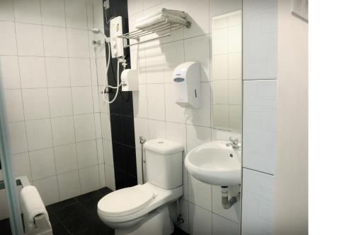 a white bathroom with a toilet and a sink at Brezza Hotel Lumut in Lumut