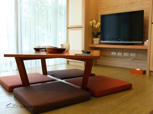 a living room with a table and a tv at ISPAVITA B&B Resort in Jiaoxi