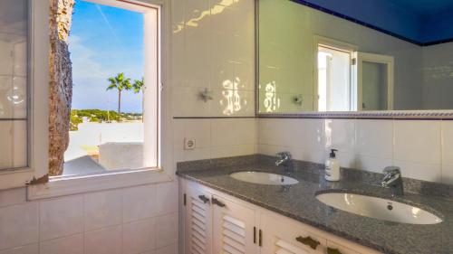a bathroom with two sinks and a window at La Chamade Cala Dor in Santanyi