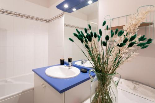 a bathroom with a sink and a vase with flowers at T2 avec terrasse proche plages in Pléneuf-Val-André