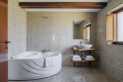 a bathroom with a tub and a sink at Turismo Rural No Gerês in Carvalheira