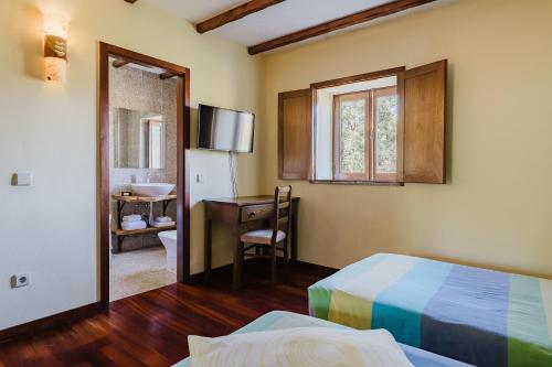 a bedroom with a bed and a desk and a window at Turismo Rural No Gerês in Carvalheira