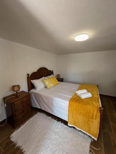 a bedroom with a large bed with a yellow blanket at Alojamento Local Vale dos Vascos in Alvaro