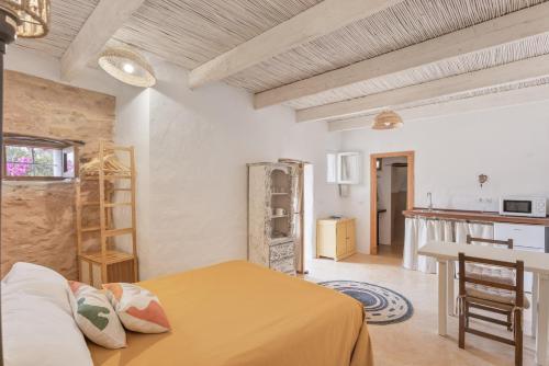 a bedroom with a yellow bed and a kitchen at Can Xicu in Illes Balears
