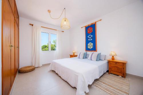 a white bedroom with a bed and a window at Casa Inés in Cala Murada