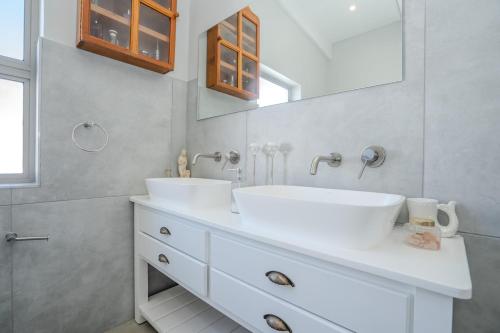 a white bathroom with two sinks and a mirror at Our Father in Paternoster