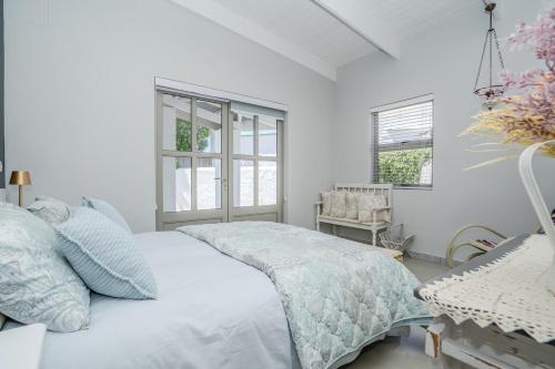a white bedroom with a bed and a chair at Our Father in Paternoster