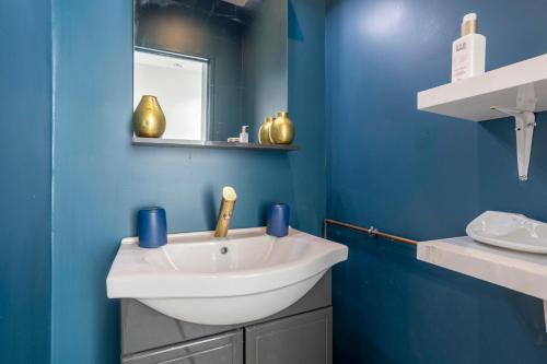 a bathroom with a white sink and a blue wall at L'Eclose Chambre Ildut in Le Guilvinec