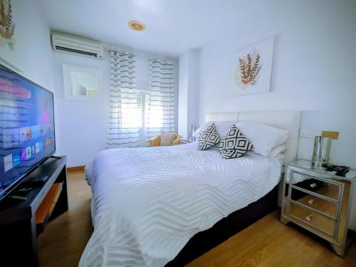 a bedroom with a bed and a flat screen tv at Duquesa Beach in Torrevieja