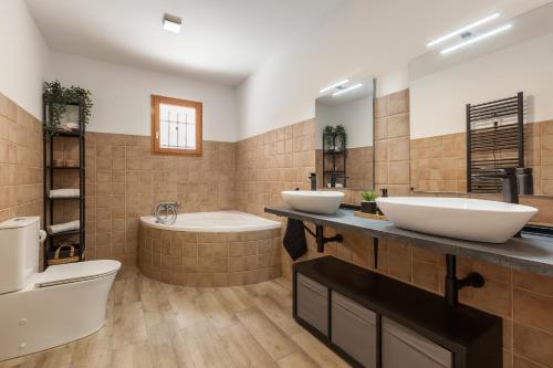 a bathroom with two sinks and a tub and a toilet at Les Roques in Castellnou de Bages