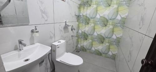 a white bathroom with a toilet and a sink at Periyar Inn in Thekkady