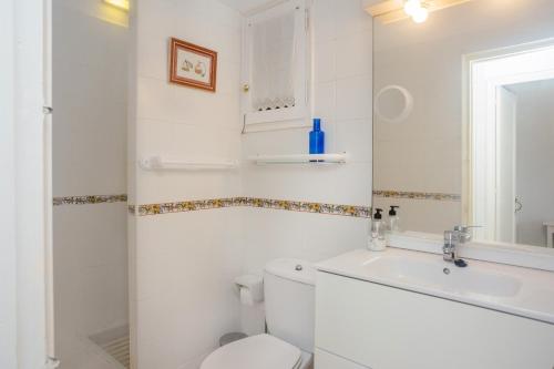a white bathroom with a toilet and a sink at El Faro 8 in Cala en Bosc