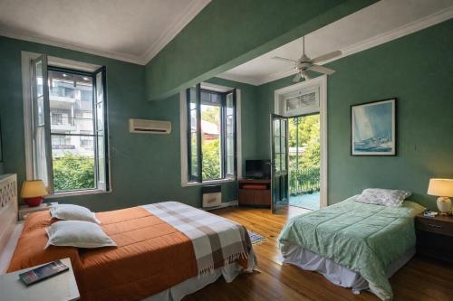 a bedroom with green walls and a bed and windows at Hotel Posada de 1860 in Tigre