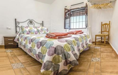 a bedroom with a bed with a comforter and a chair at Villa Godoy in Periana