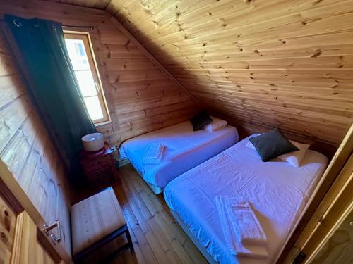 two beds in a log cabin with a window at Chalet Belfort in Penhas da Saúde