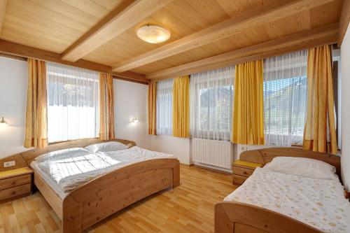 a bedroom with two beds and two windows at Hatzlhof Appartements in Vipiteno