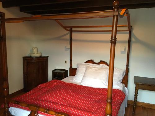 a bedroom with a canopy bed with a red comforter at Chaleureuse Maison de Montagne in Garin