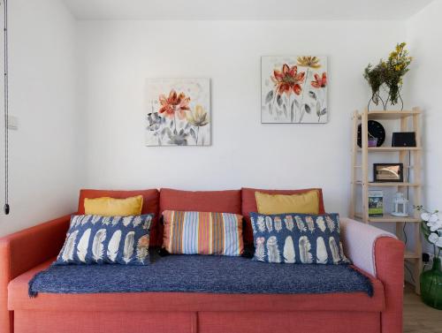 a orange couch with colorful pillows in a living room at Casa Dona Florinda in Ermida