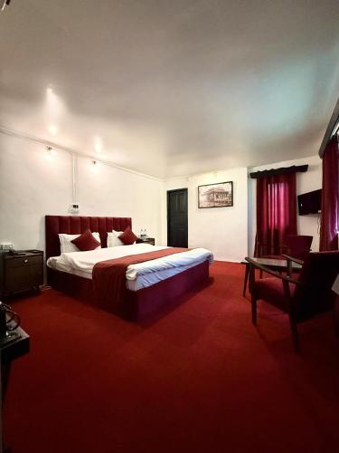 a bedroom with a large bed and a red carpet at Riverdale by Stay Pattern in Pahalgām