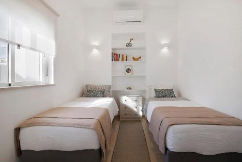 two beds in a room with white walls at Moncoração Village in Moncarapacho