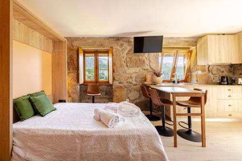a bedroom with a bed and a desk and a kitchen at Estúdio à Beira da Água no Gerês in Geres