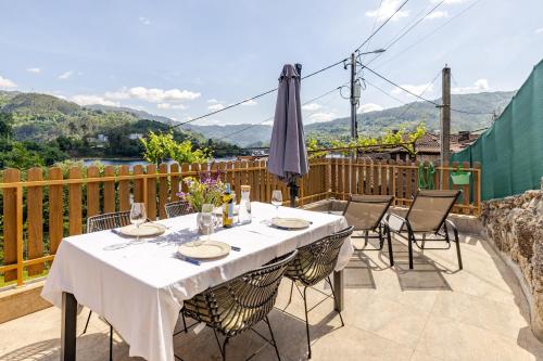 a table with chairs and an umbrella on a patio at Estúdio à Beira da Água no Gerês in Geres
