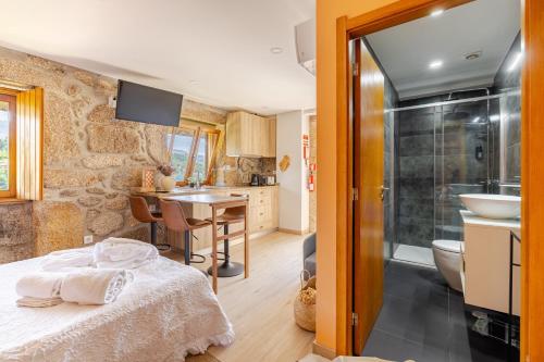 a bedroom with a bed and a bathroom at Estúdio à Beira da Água no Gerês in Geres