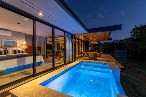 a house with a swimming pool and a bedroom at Morro Redondo - Bangalôs com vista do lago e da serra in CÃ¡ssia