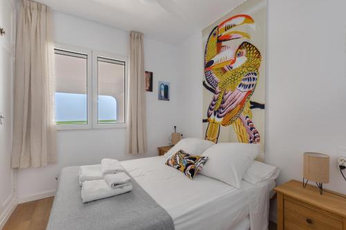 a bedroom with a white bed with a large bird on the wall at Casa Golf in Son Parc