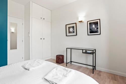 a white bedroom with a bed and a black table at Exception Maison pieds dans l'eau in Fréjus