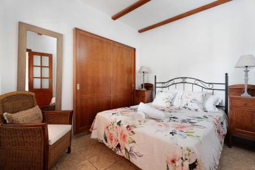 a bedroom with a bed with a floral bedspread and a chair at Casa Rodri in Puntagorda