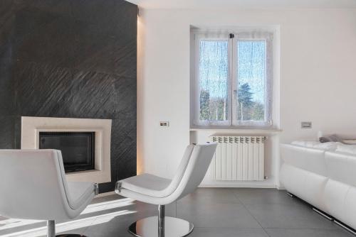 a living room with two white chairs and a fireplace at Villa Luna Al Lago in Biandronno