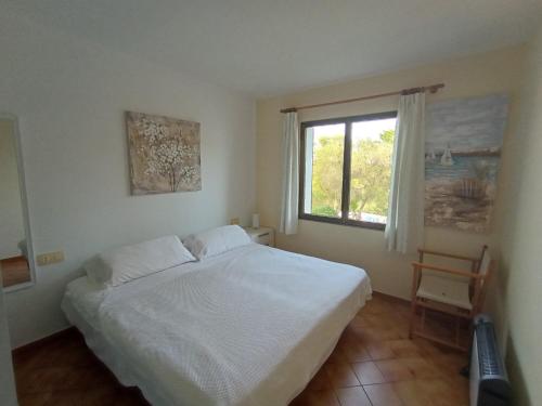 a bedroom with a white bed and a window at Villetta Son Bou in Son Bou