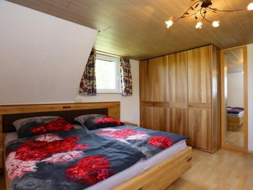 a bedroom with a bed with red flowers on it at Ferienwohnung Beim Falkner, 60qm in Königsfeld im Schwarzwald
