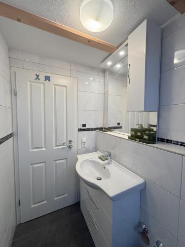 a bathroom with a white sink and a white door at Good Habits in Kleinengstingen