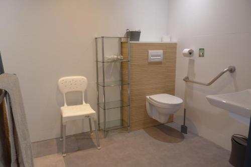 a bathroom with a toilet and a chair and a sink at Studio L'Erdre au moulin - terrasse in Joué-sur-Erdre