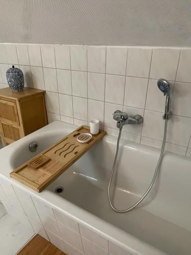 a bath tub with a shower with a wooden tray at Gutsherren Räume in Groß Upahl