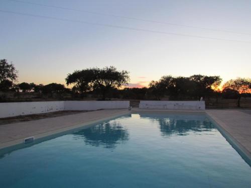 a swimming pool with a sunset in the background at Monte Azul, Um Oásis No Alentejo in Vimieiro