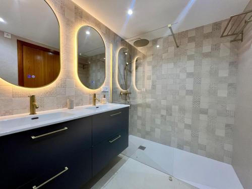 a bathroom with a sink and two mirrors at Altea La Nova in Bernia