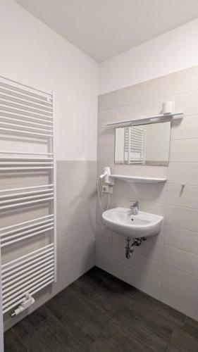 a white bathroom with a sink and a mirror at CVJM Peregrinus Herberge in Görlitz