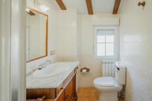 a white bathroom with a sink and a toilet at San Pelayo in San Millán de Lara