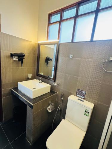 a bathroom with a toilet and a sink and a mirror at The Bay in Arugam Bay