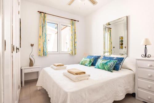 a bedroom with a bed with blue pillows and a mirror at Apartamento Dos Geckos in Son Parc