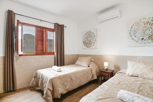 a bedroom with two beds and a window at Casa Abuela Nicolasa in Máguez