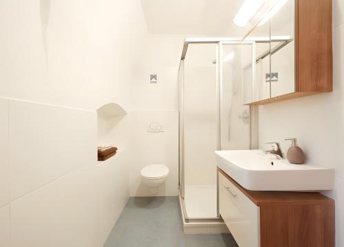 a white bathroom with a sink and a shower at Rafaser - Apartment Albina in Feldthurns