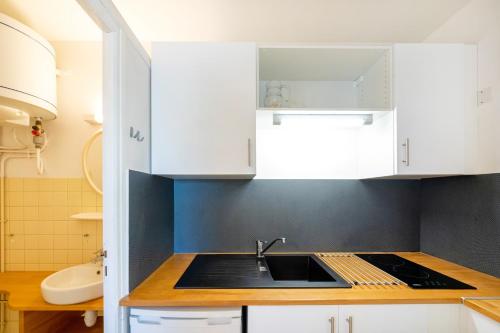 a kitchen with white cabinets and a sink at Les Mimosas - Appartement 10 in Cazaubon